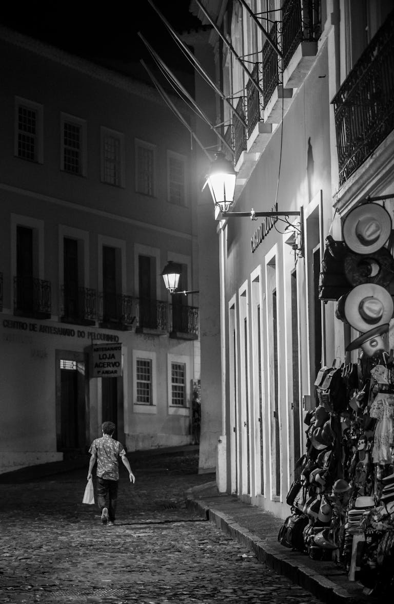 Grayscale Photo of a Man Walking on the Street