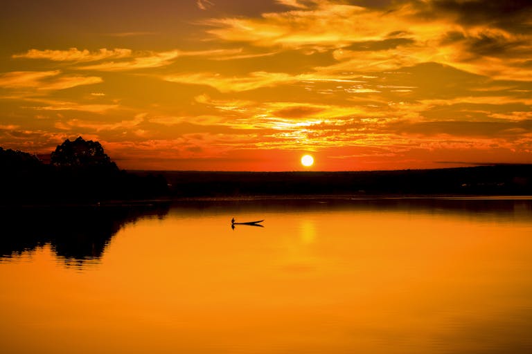Picturesque view of bright lake under cloudy sky at sunset